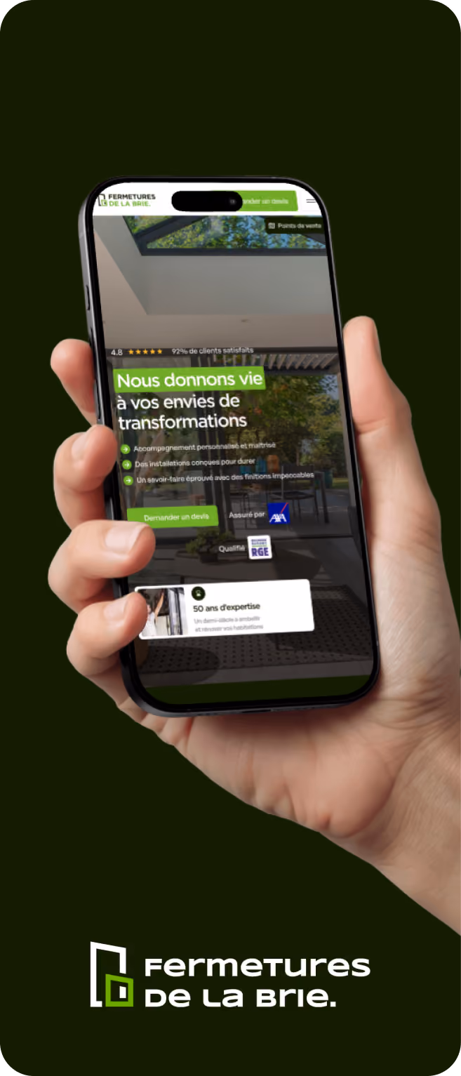 Main tenant un smartphone affichant un site de Fermetures de la Brie avec texte sur les transformations et expertise.