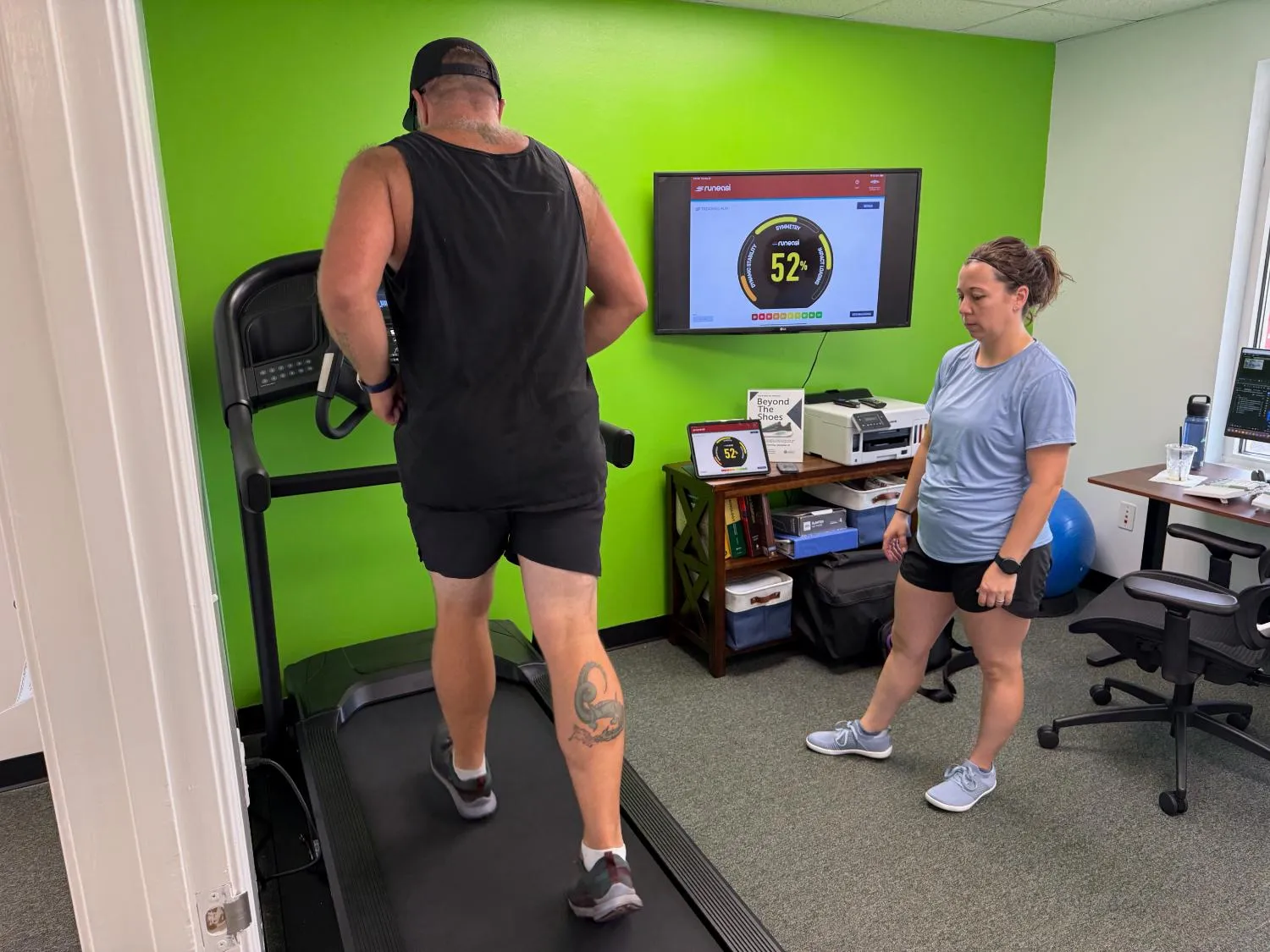 Physical therapist monitoring a client's heart rate during treadmill running analysis.