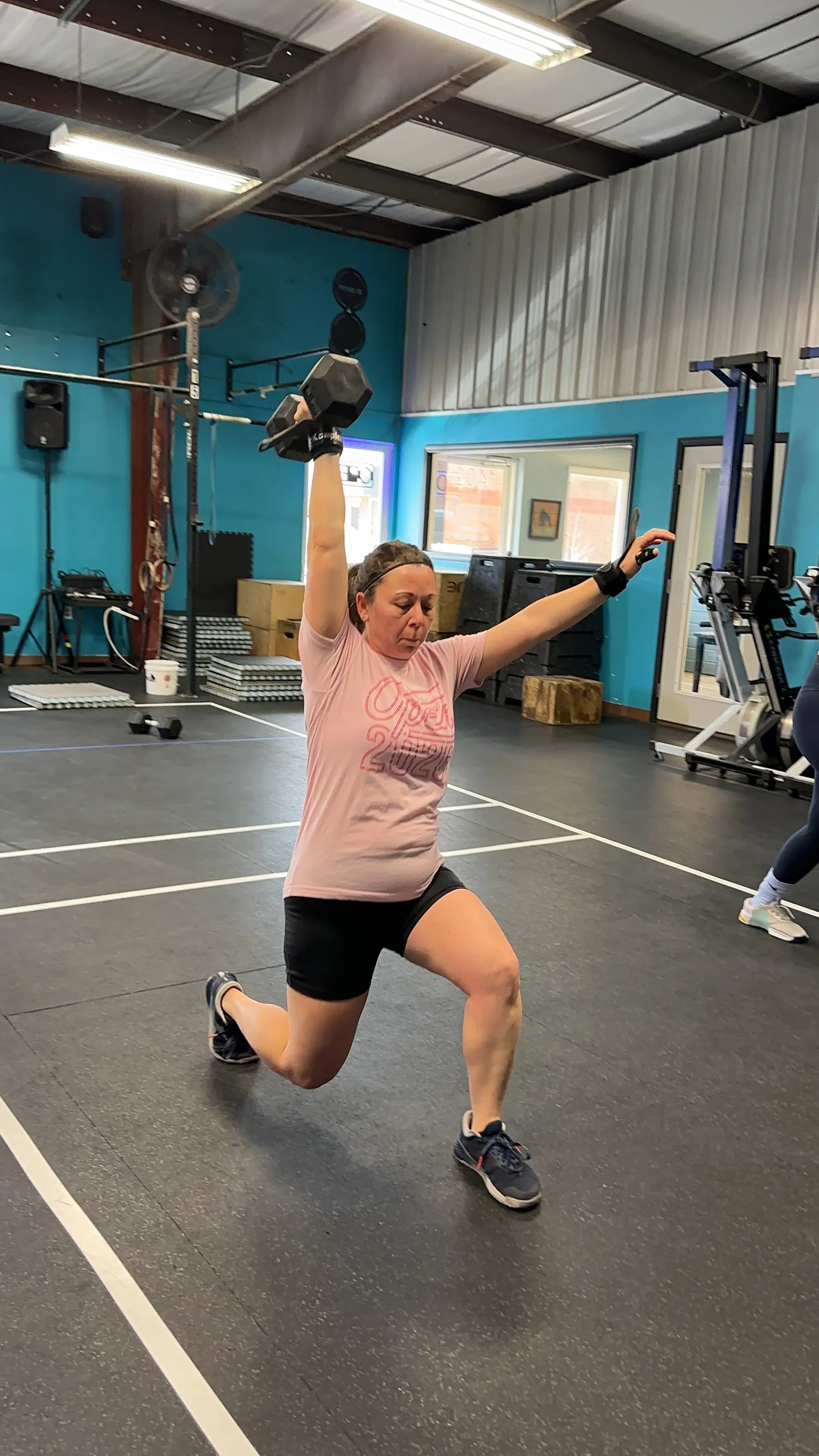 Client performing a reverse lunge with an overhead dumbbell at Proactive Kinetics in Murfreesboro, Tennessee.