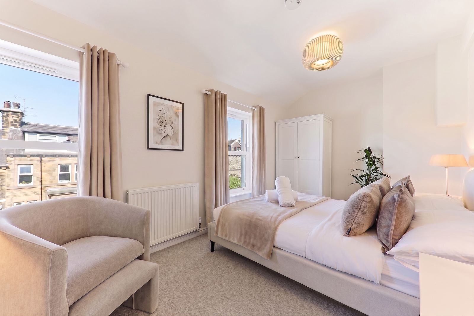 Bright bedroom with an armchair and a view of Harrogate stone terraces at Mayfield Three