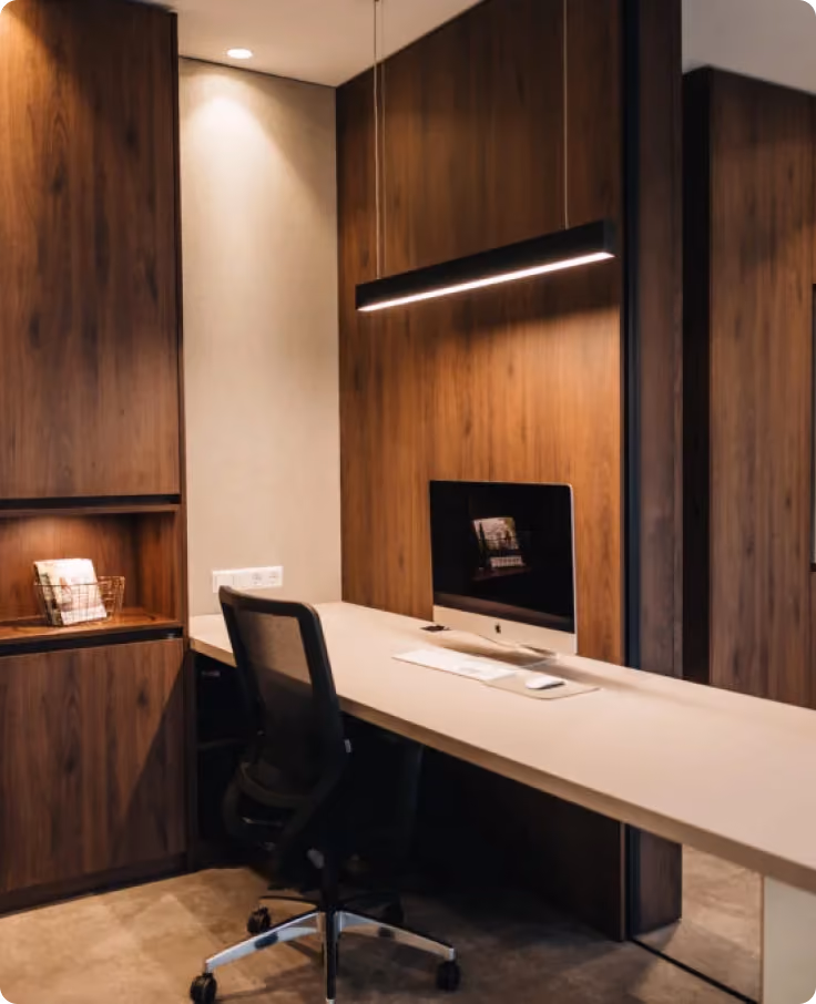 Moderner Arbeitsbereich mit Holzverkleidung, Schreibtisch, Computer und ergonomischem Bürostuhl.