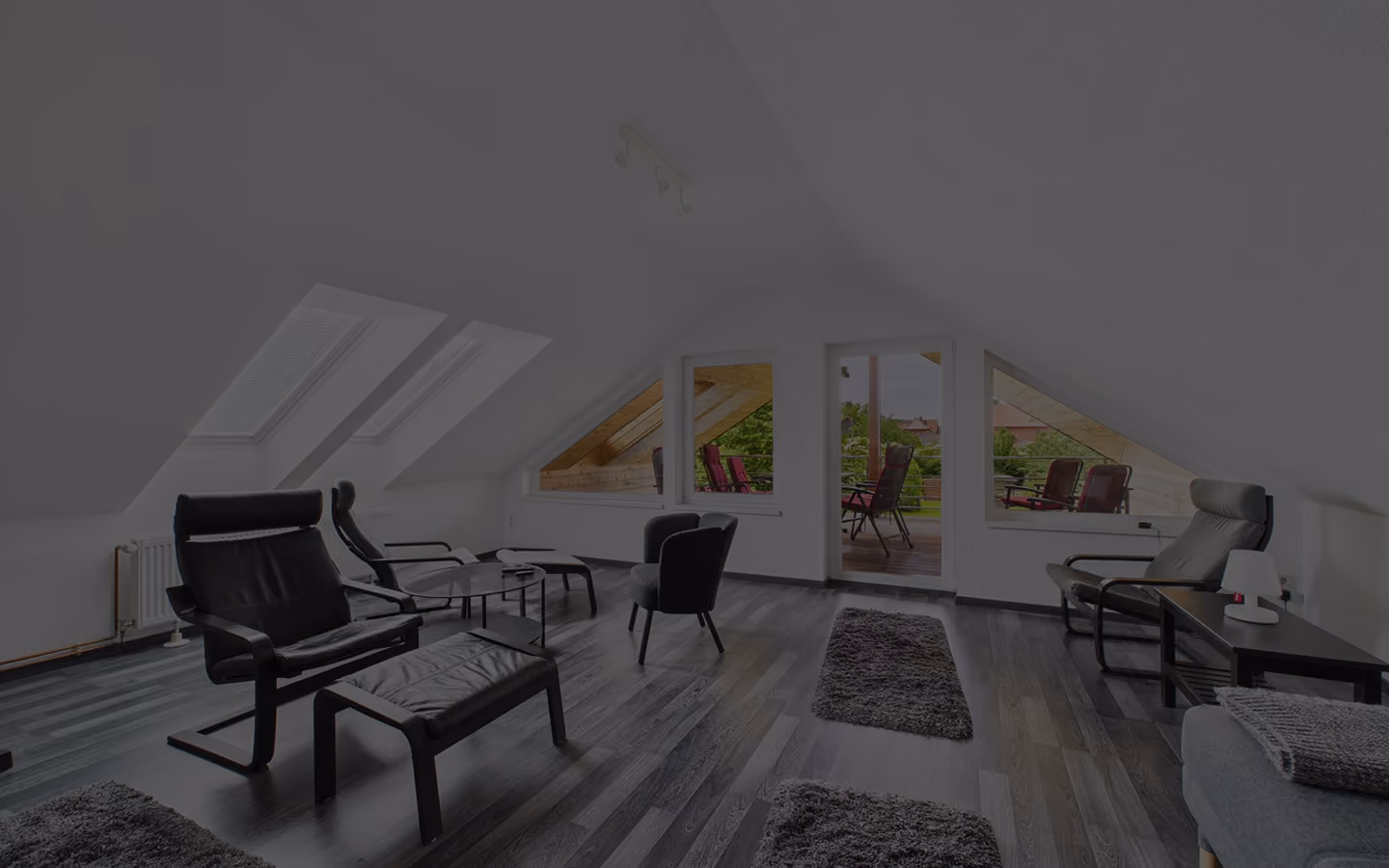 Moderne Dachgeschosswohnung mit schwarzen Sesseln und Zugang zu Terrasse mit Gartenblick.