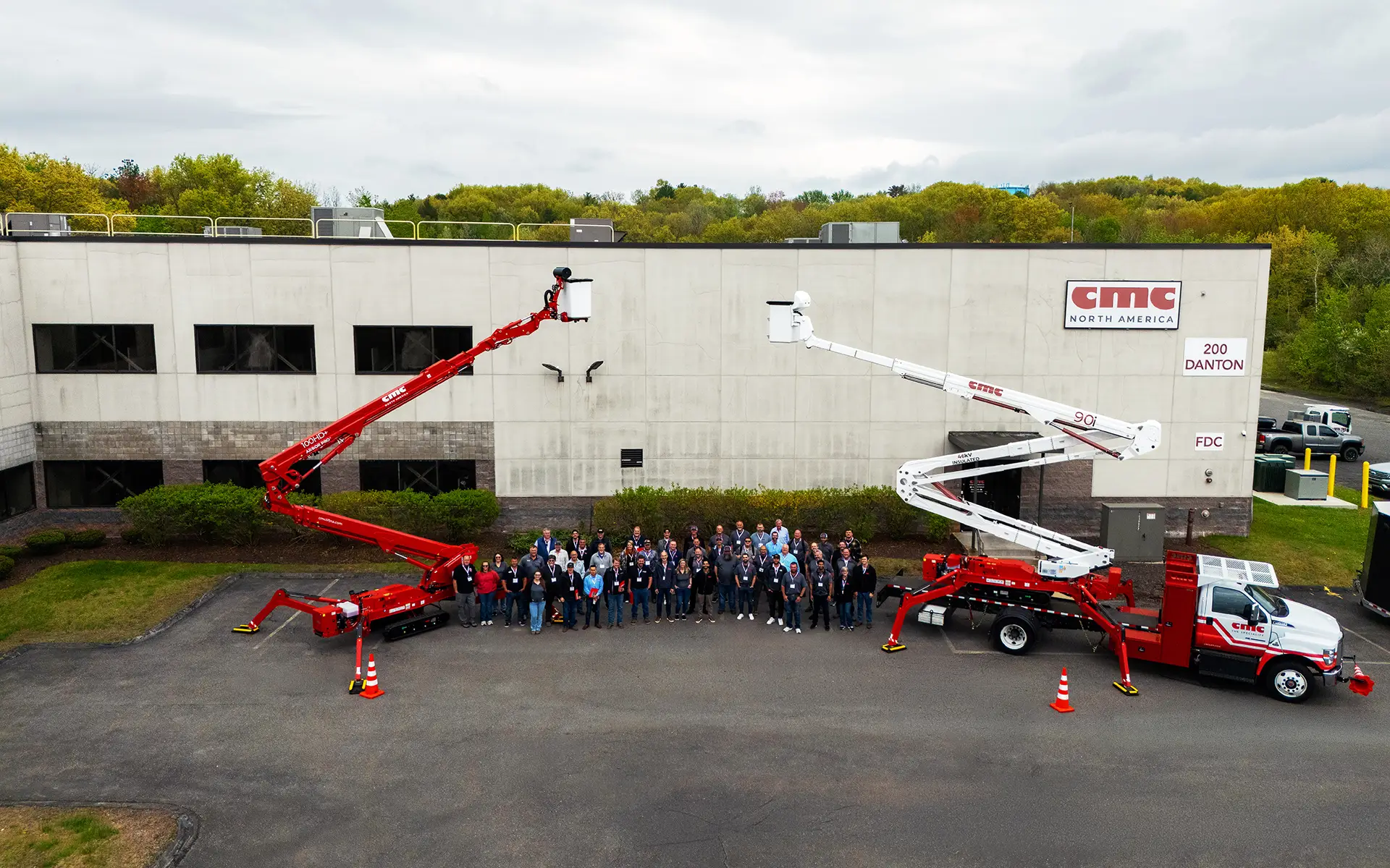 CMC North America team standing outside headquarters between two spider lift cranes