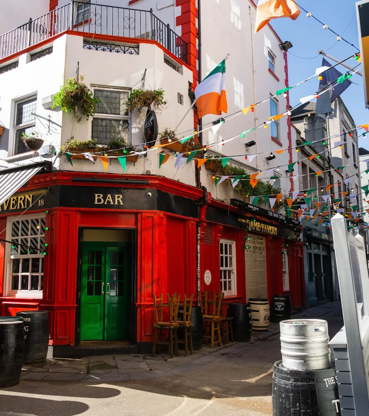 Red corner bar with green doors and Irish flags and bunting strung above the street.