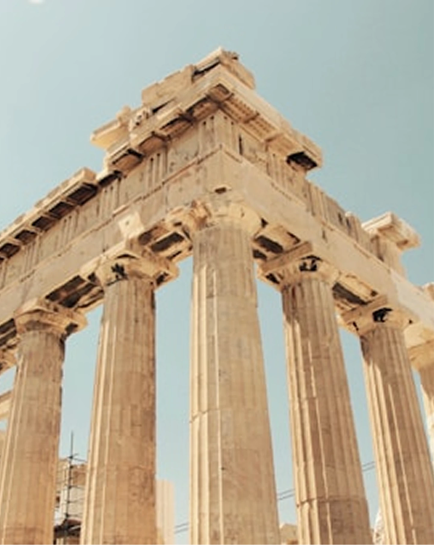 Close-up of ancient Greek columns and entablature under clear blue sky.