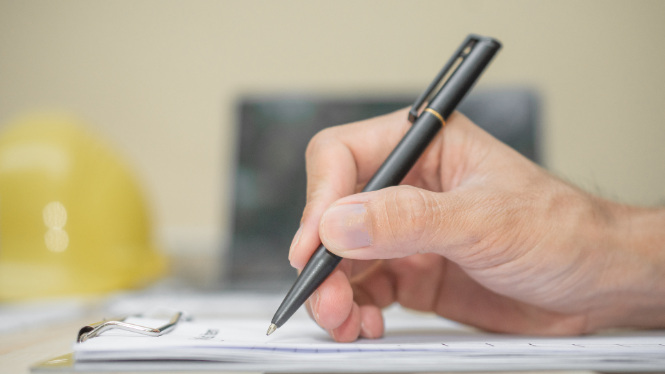 Alt text: A person writing on a piece of paper with a pen