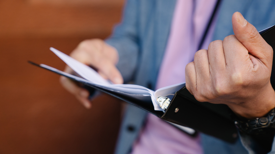 A person in a suit holding a binder