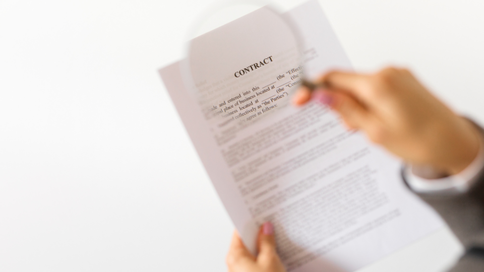 A person holding a magnifying glass over a contract