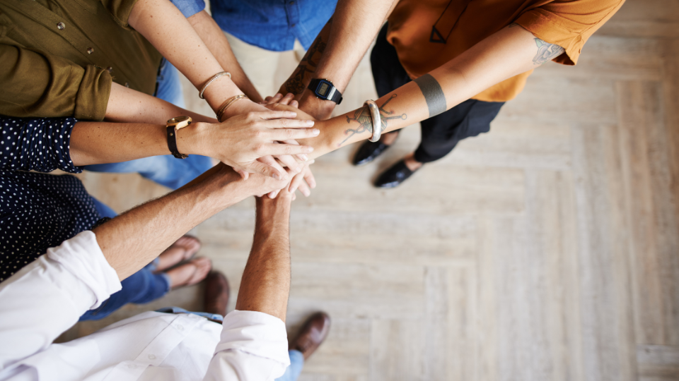 Alt text: A group of people putting their hands together in a circle