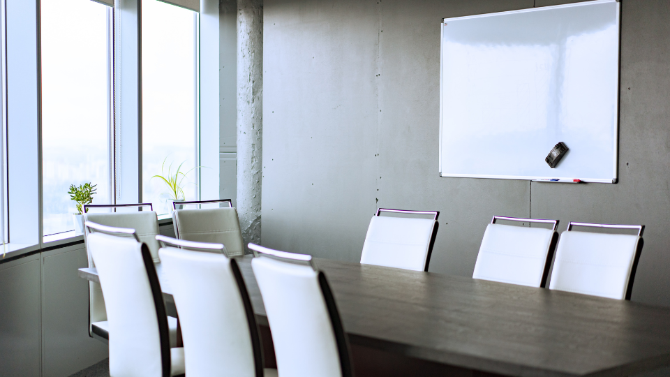 Alt text: An empty conference room with a whiteboard on the wall