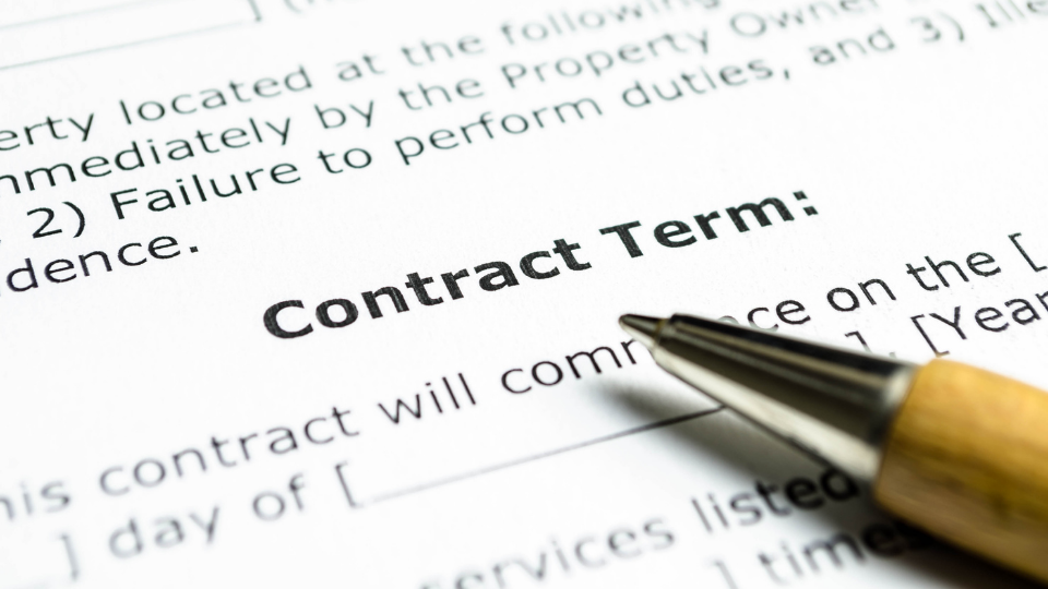 Alt text: A pen resting on top of an open contract, with the contract terms clearly visible