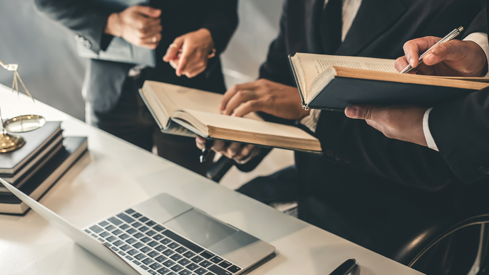 A group of business people working around a desk with a laptop and legal books