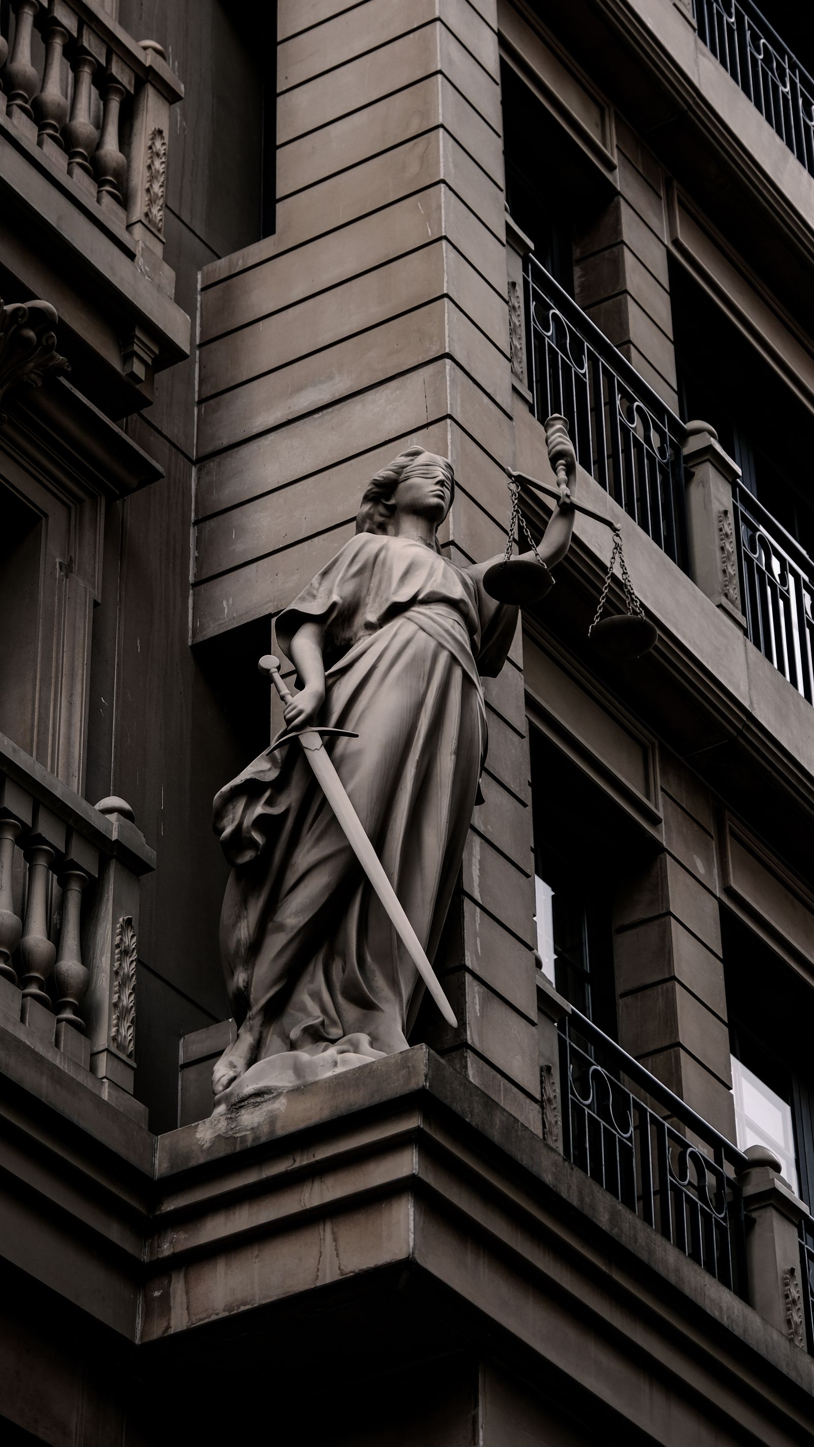 Lady Justice statue with scales and sword on a historic building facade