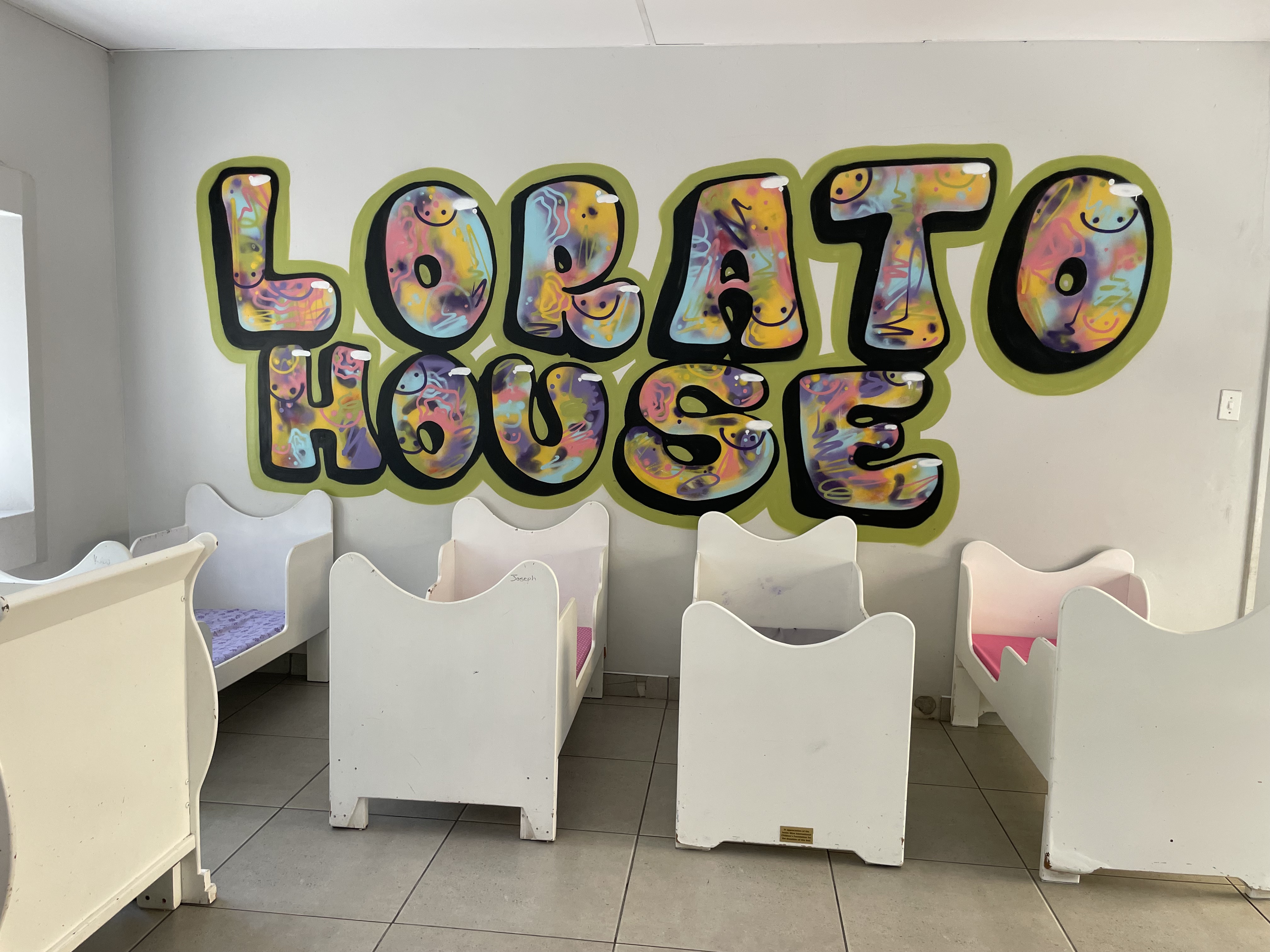 Beds in a Lorato House bedroom, with the Lorato House mural on the wall