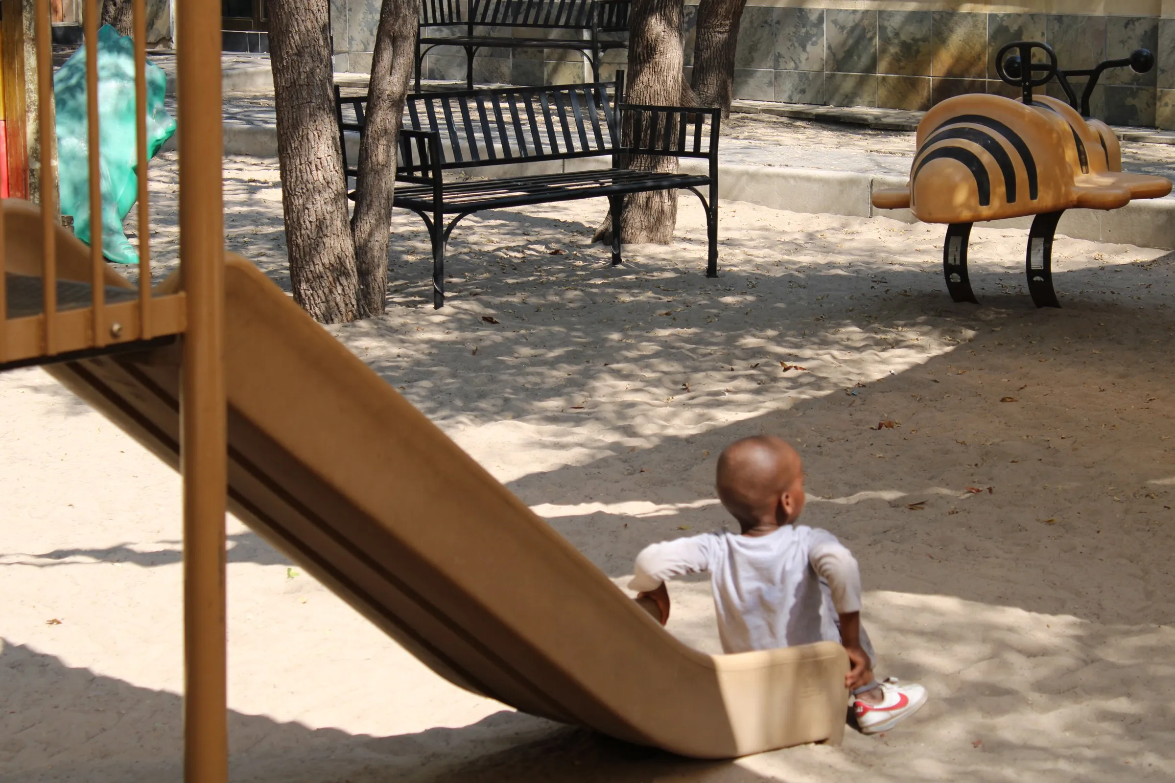 A child at the bottom of the slide in the Lorato House playground