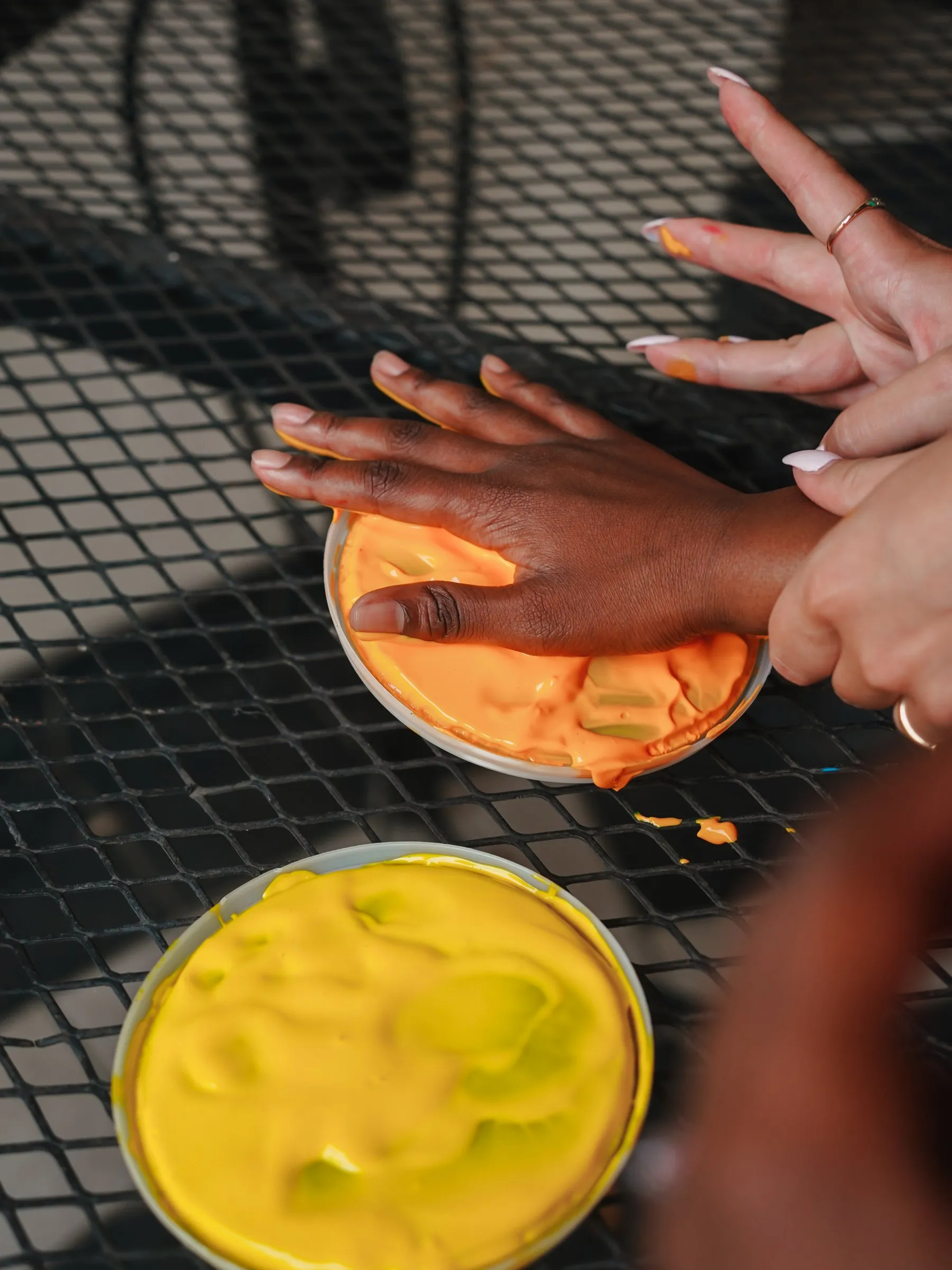 A child's paint-covered hands over a plate of paint during a craft activity