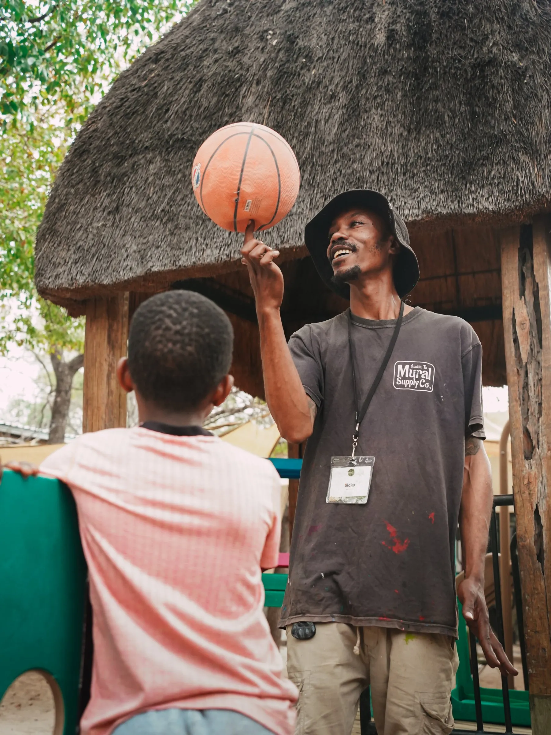 A Lorato House team member spinning a basketball for a child in the playground
