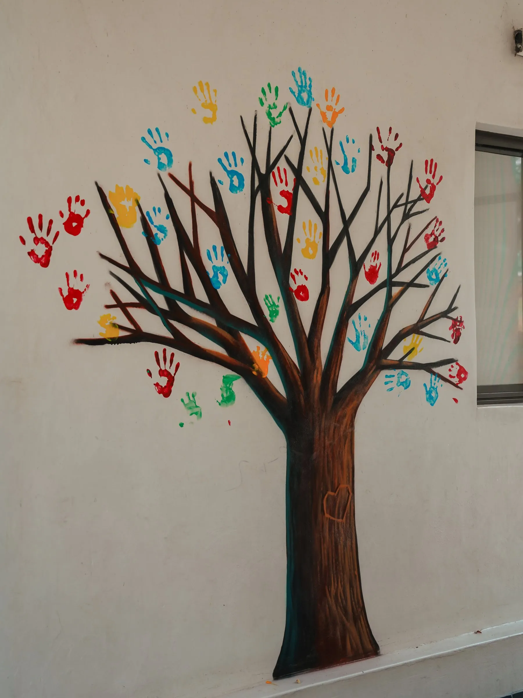 The painted handprint tree mural at Lorato House