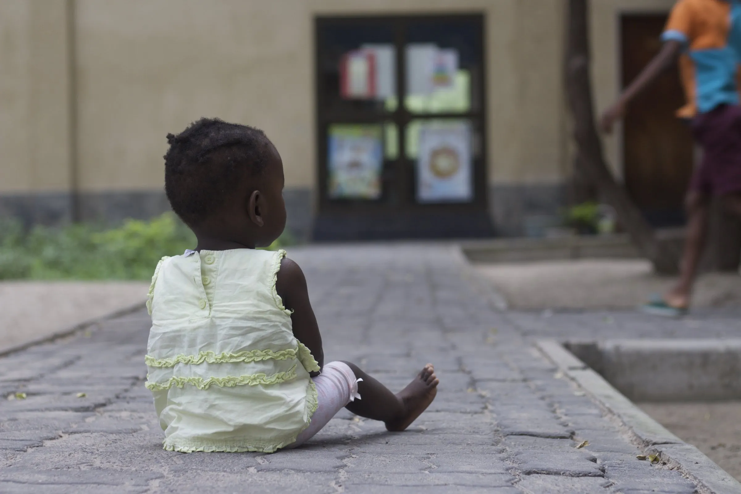 A toddler walking across the Lorato House courtyard, seen from behind