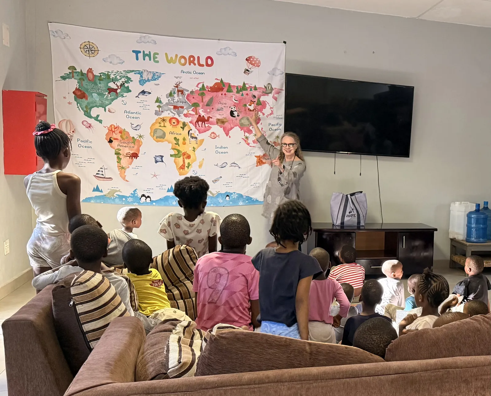Children seen from behind during a lesson in front of a world map