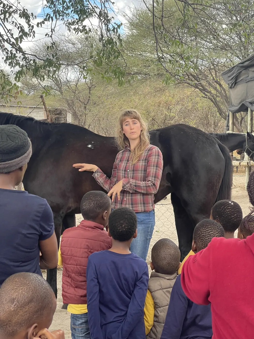 Children seen from behind meeting a horse with a volunteer