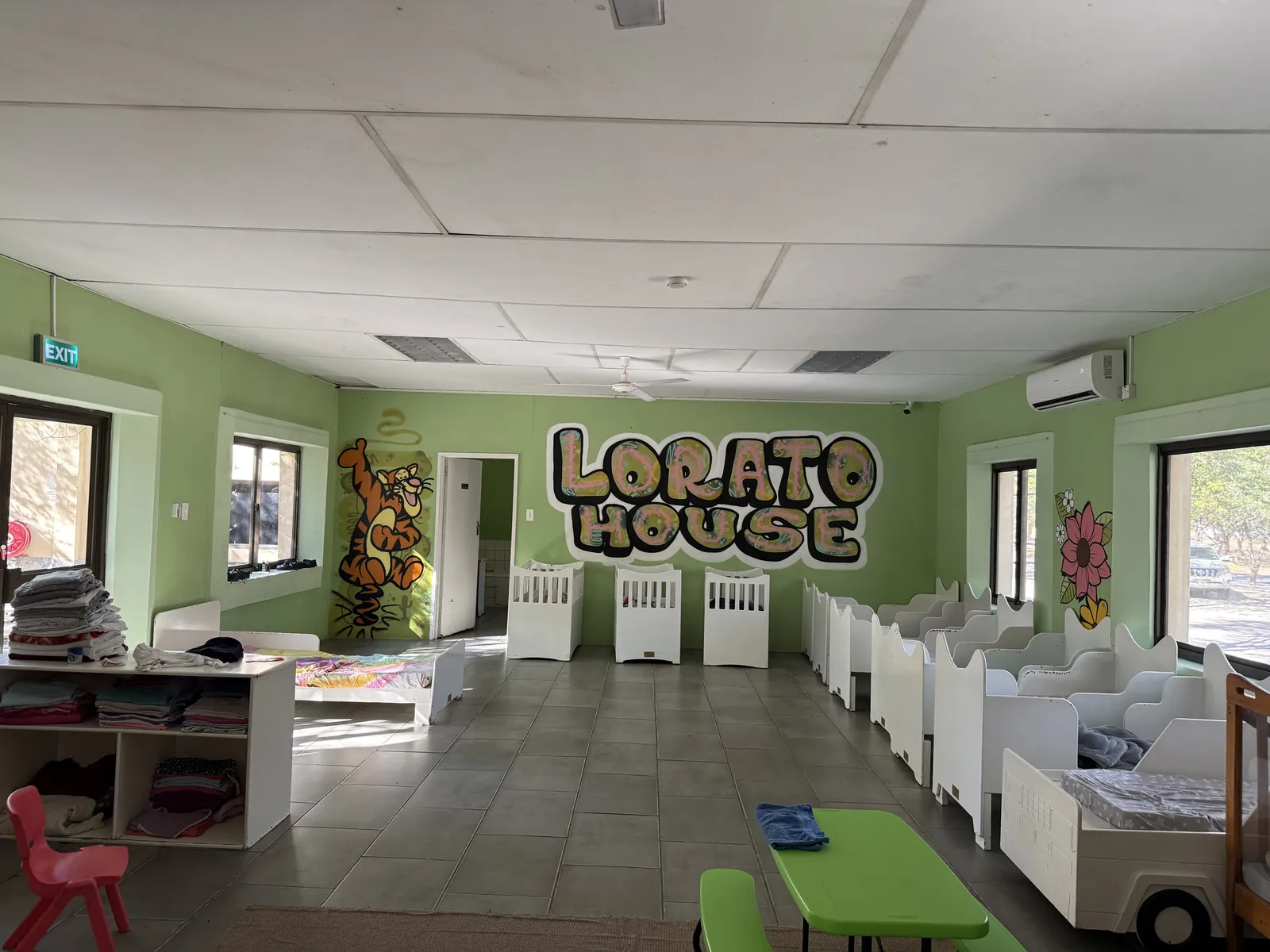 A nursery room at Lorato House with cots and the Lorato House mural