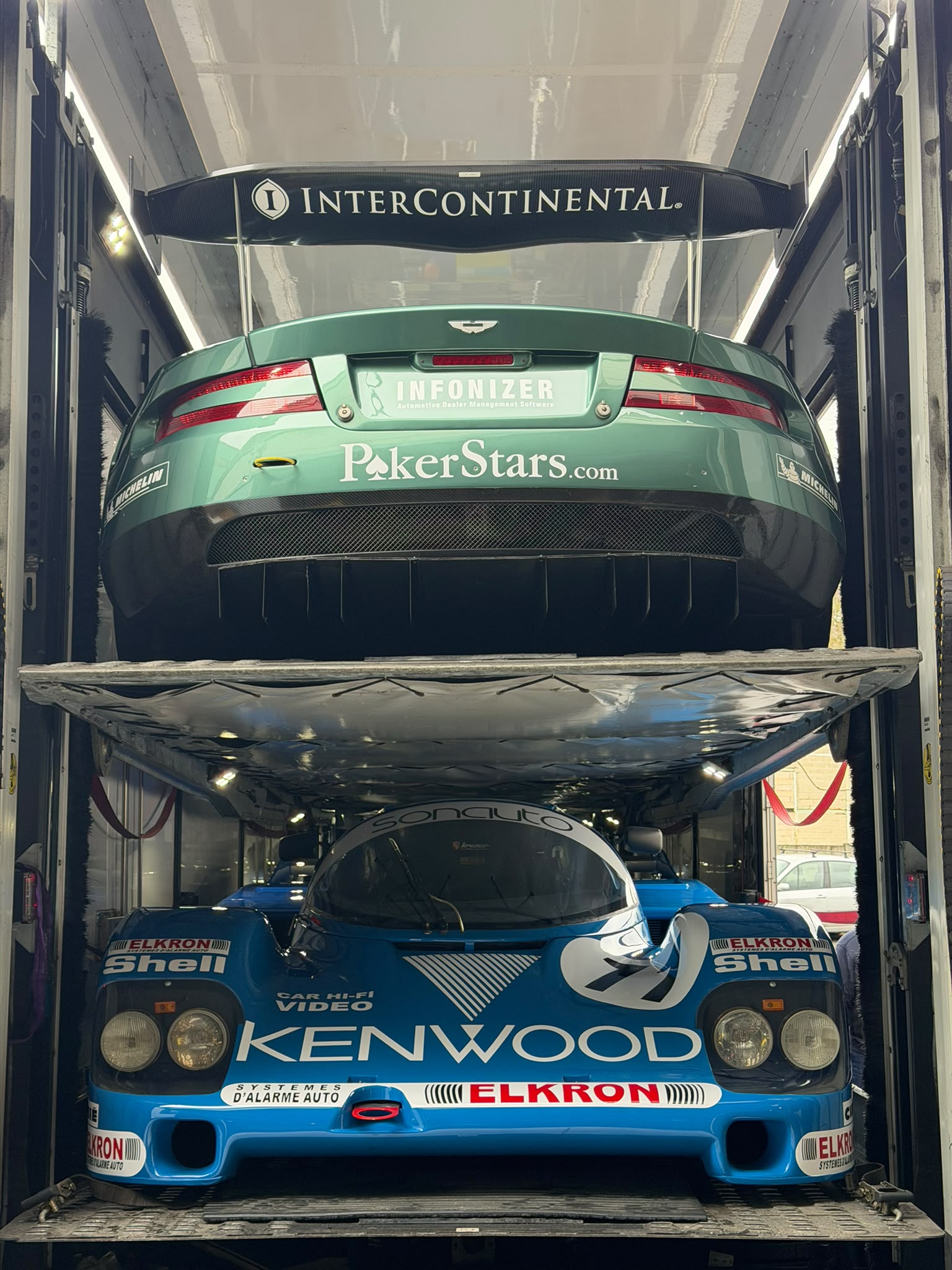 Porsche 962 et Aston Martin chargées à étages dans un camion fermé de transport de véhicules