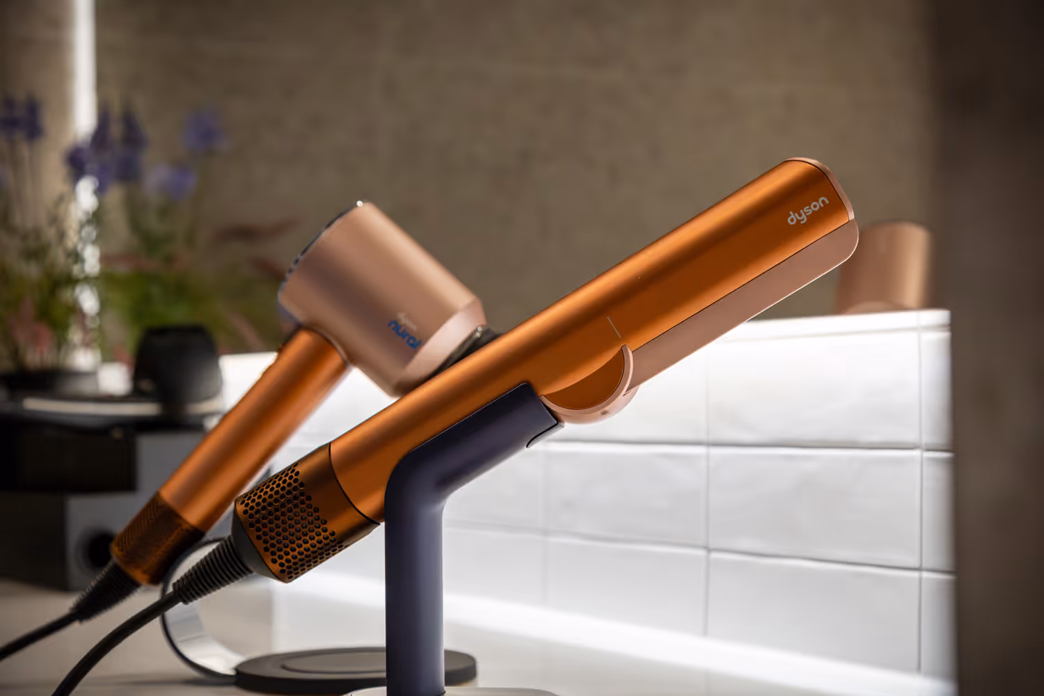 Orange Dyson hair dryer displayed on a stand with a blurred background.