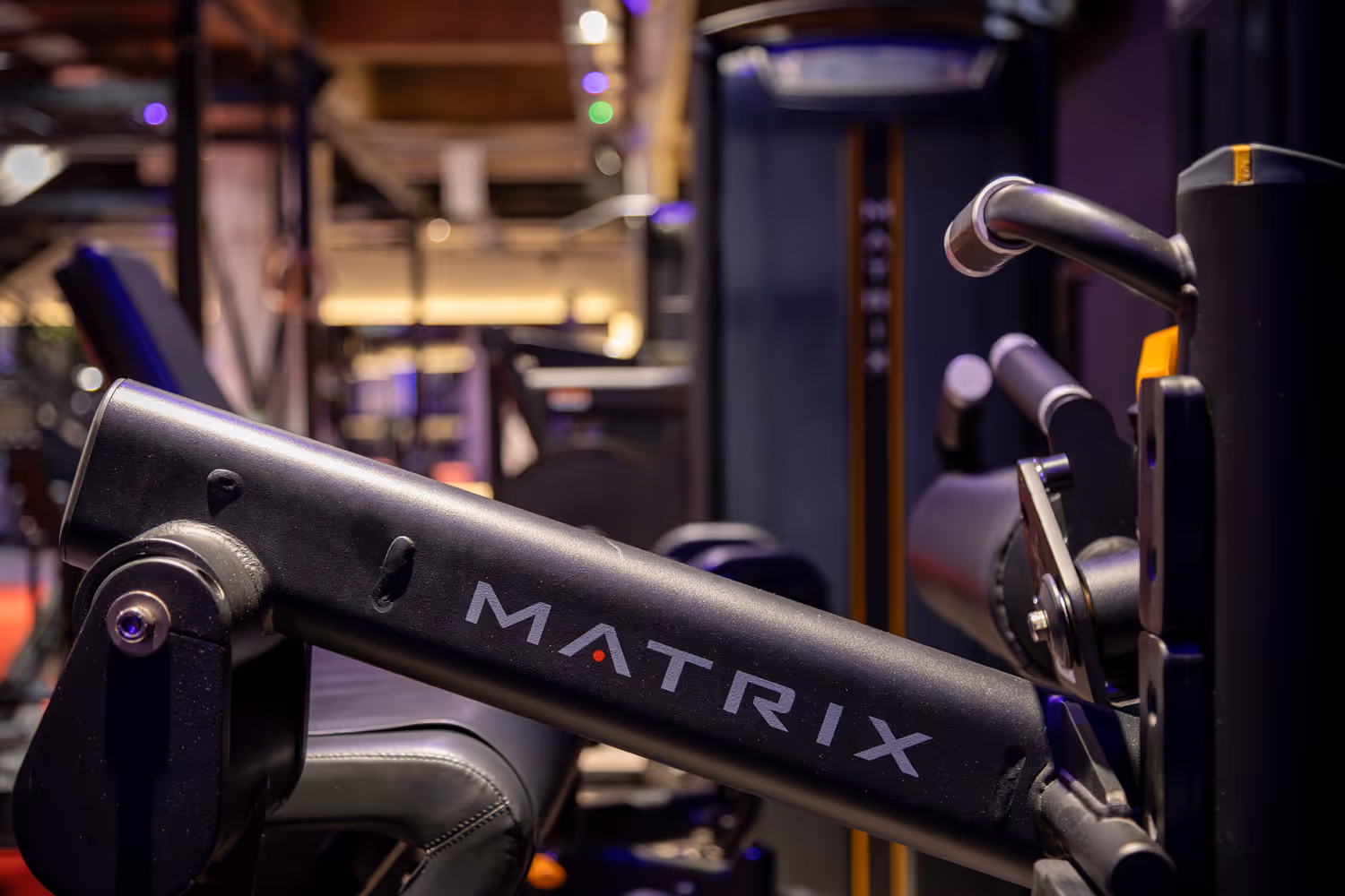Close-up of MATRIX brand gym leg exercise machine in a fitness center with blurred equipment background.