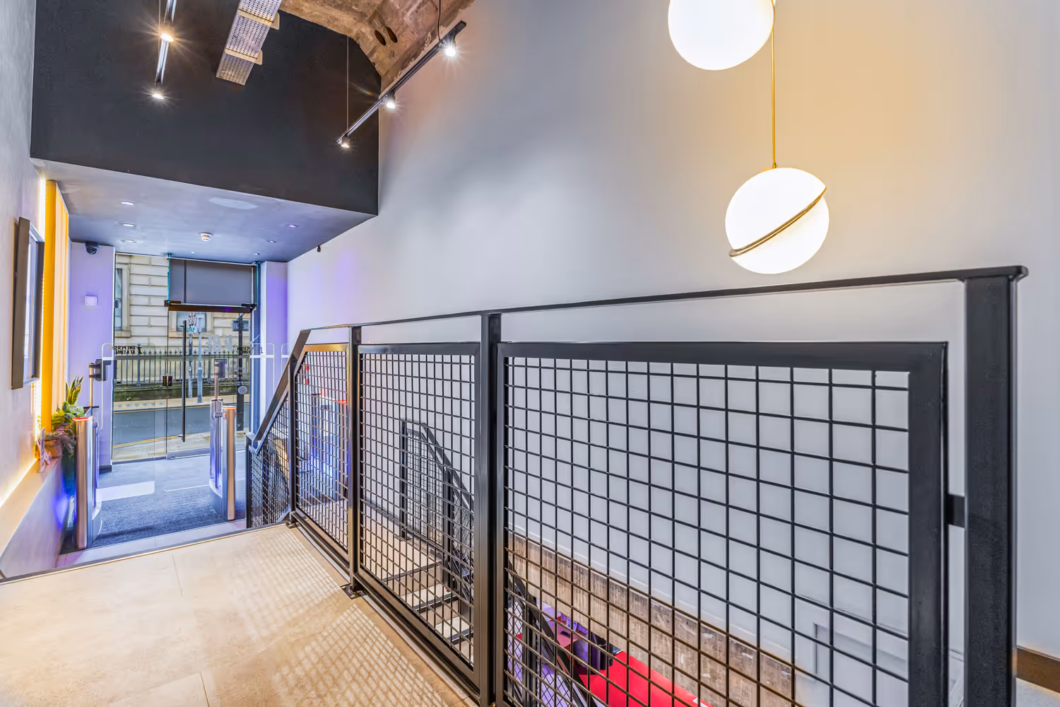 Modern staircase with black metal railing and globe pendant lights in a bright interior space.
