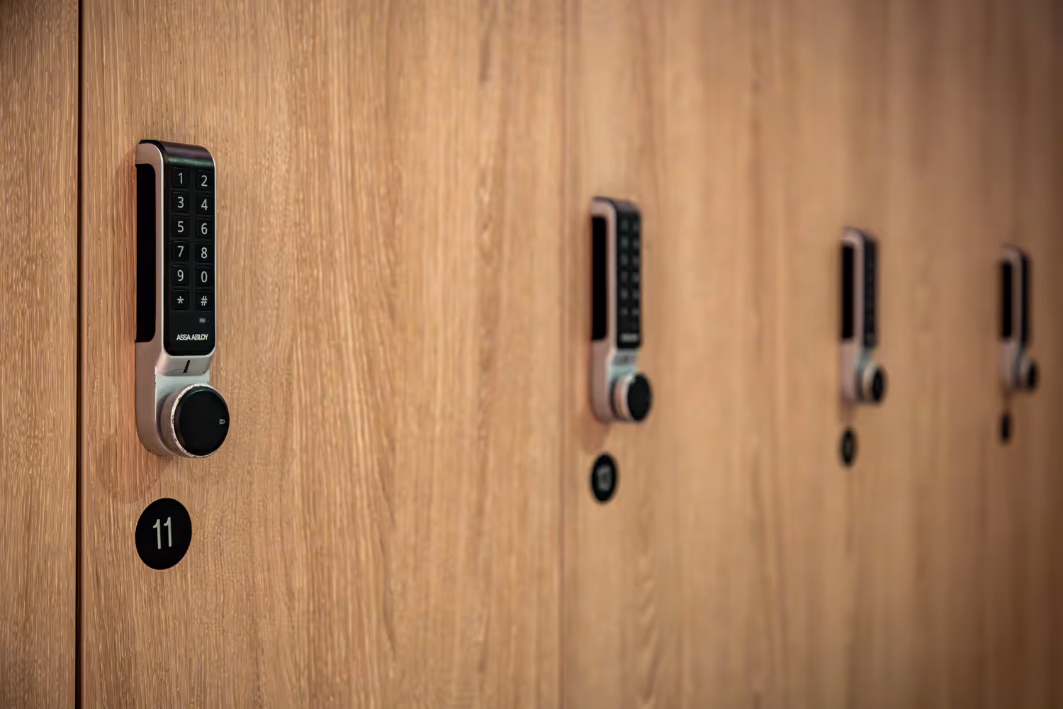 Row of wooden lockers with digital keypad locks, locker number 11 visible in focus.