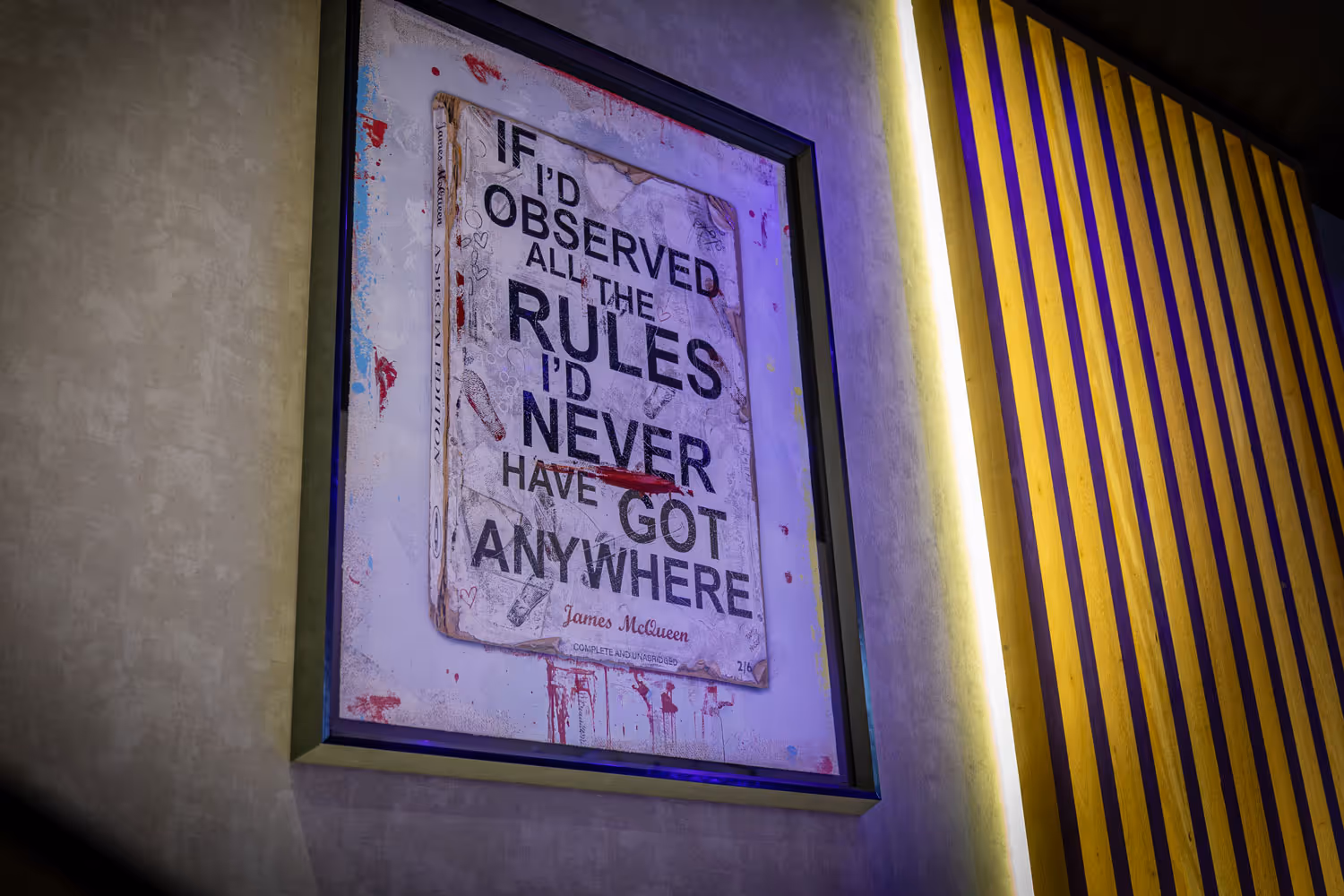Framed poster on a wall with quote by James McQueen about rules and observation.