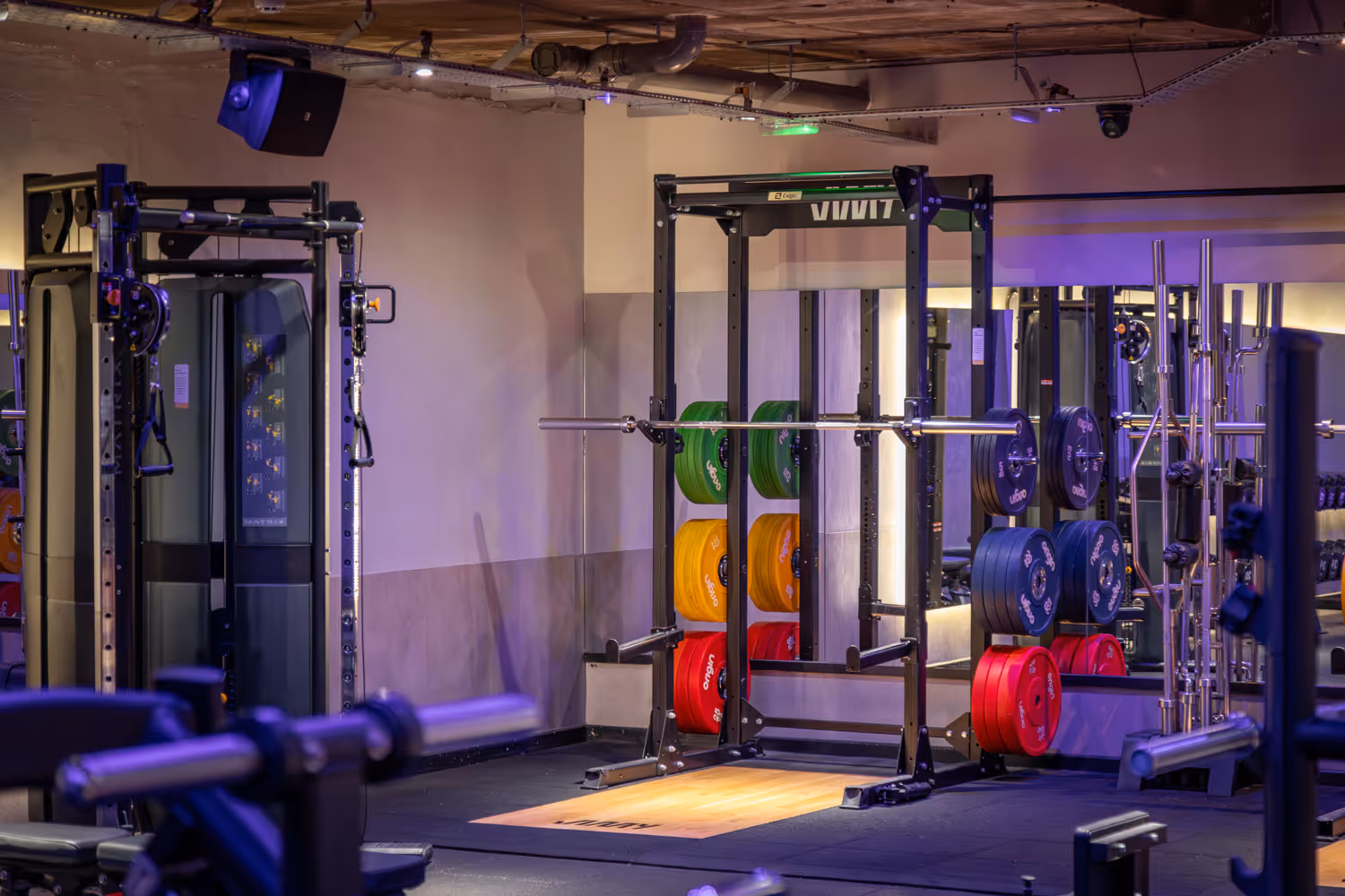 Weightlifting rack with loaded colorful plates and gym equipment in a modern fitness center.
