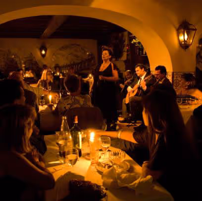 Dimly lit restaurant with diners and a singer performing next to guitarists under an arched ceiling.