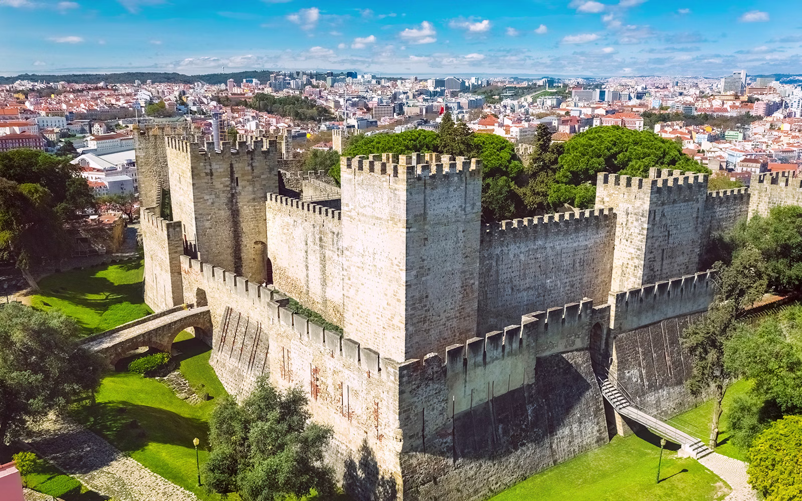Aerial view of São Jorge Castle with stone walls and towers in Lisbon under a clear sky.