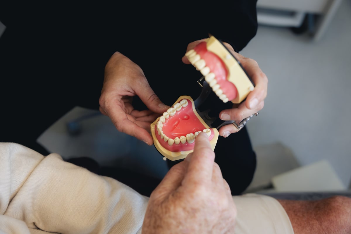 Dentist showing dental implant model to patient in treatment room