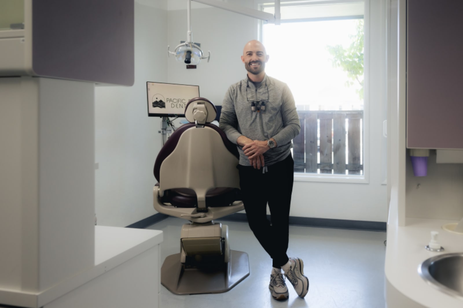 Dental professional demonstrating implant technology to patient in treatment room.