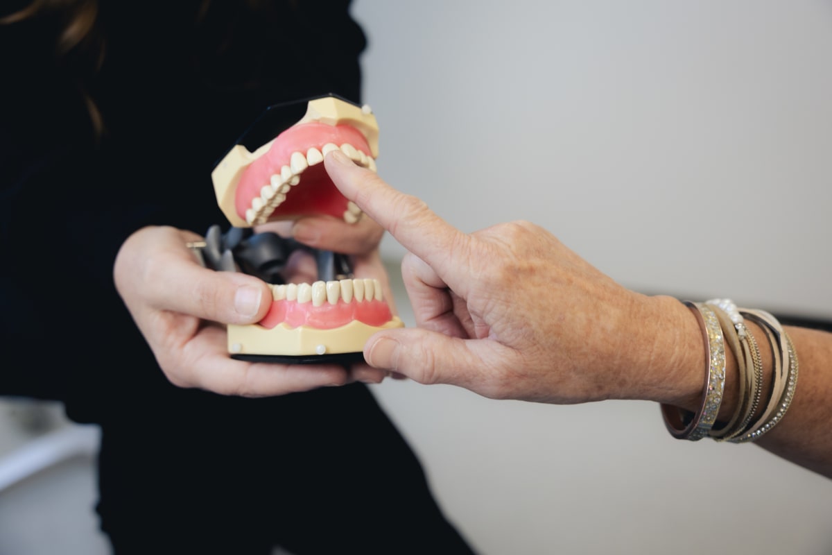 Close-up of dental restorative model showing teeth and implant structure held in hands