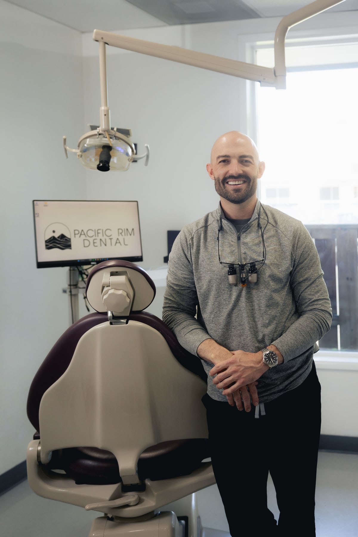 Dentist standing next to dental chair in treatment room at Pacific Rim Dental