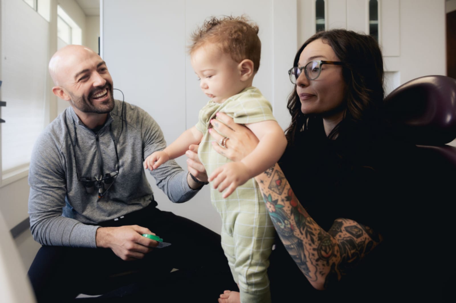 Male dentist with woman and child reviewing dental materials together
