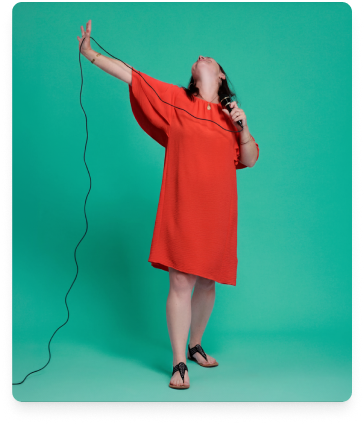Femme souriante en robe rouge tient plusieurs pinceaux avec d'autres dans ses cheveux.