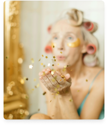 Femme souriante en robe bordeaux tenant des pinceaux avec des pinceaux dans les cheveux sur fond vert.