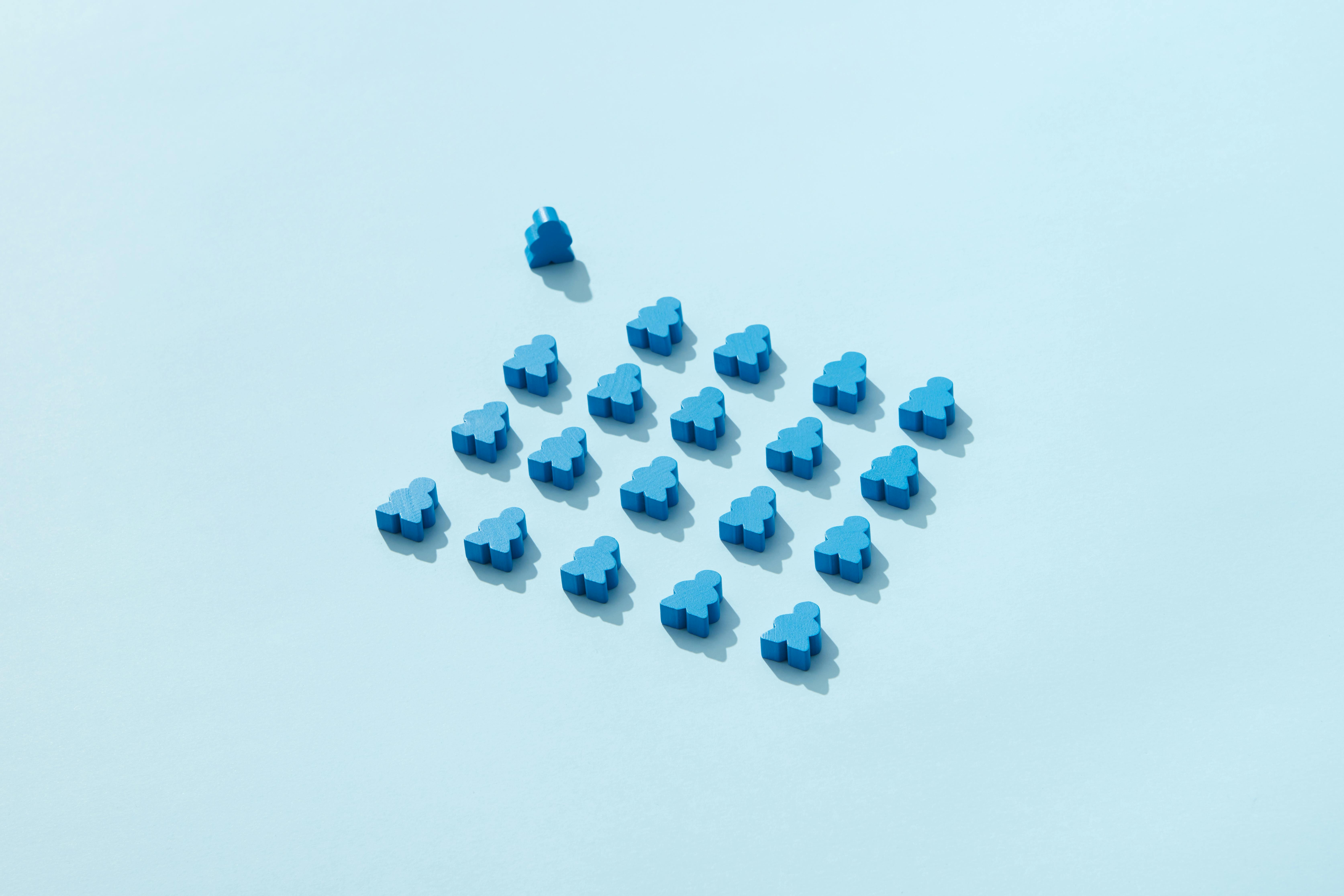 Une figurine bleue séparée d'un groupe de 23 figurines bleues sur un fond bleu clair.