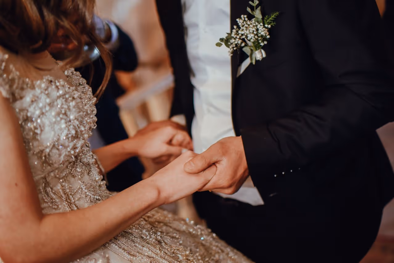 Close-up of bride and groom holding hands during wedding ceremony.