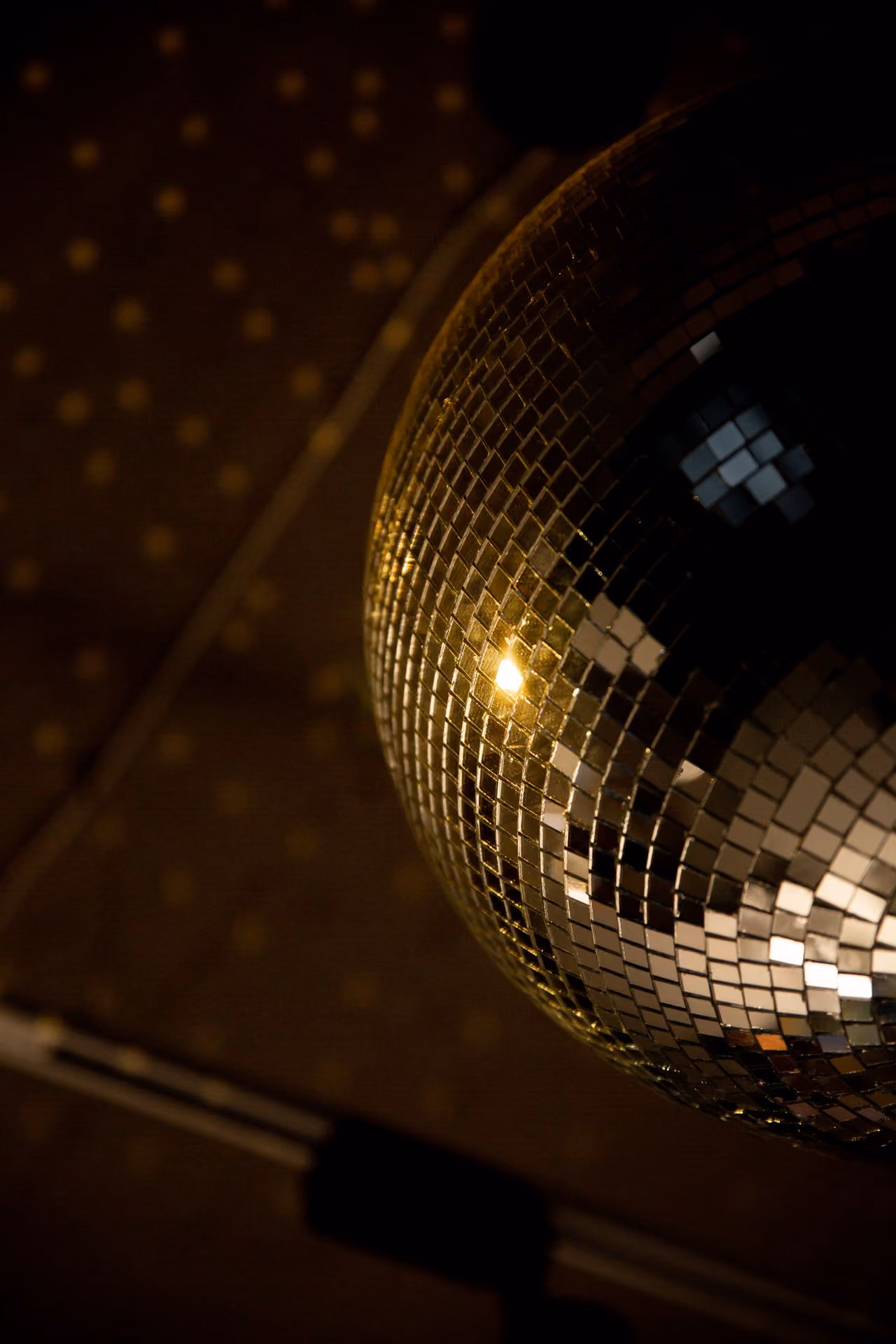 Close-up of a disco ball reflecting light squares on a dark background.