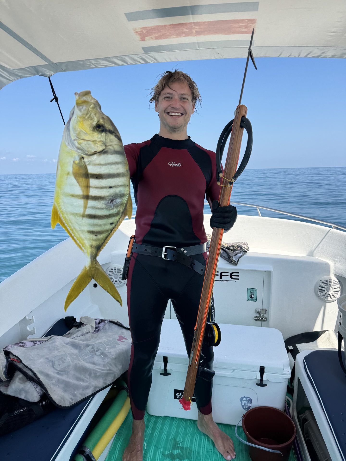 A guest in a wetsuit holding a catch on board
