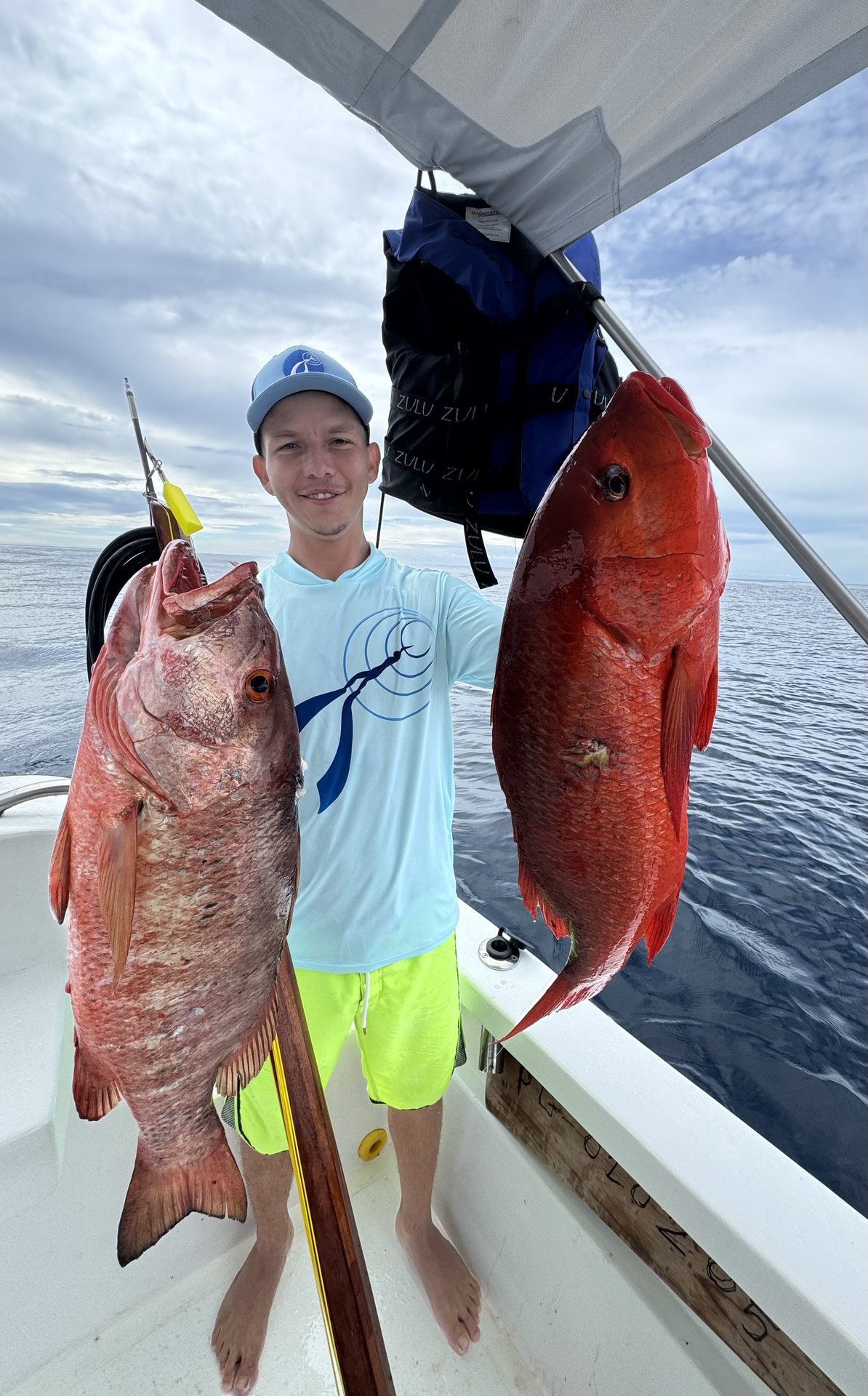 A guest holding two fish on board