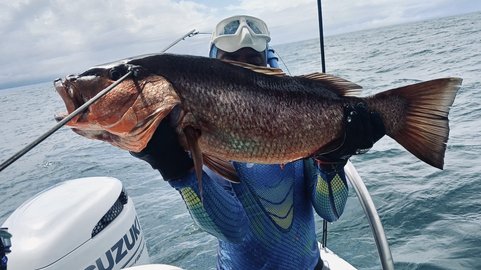 A spearfisher displaying a catch beside the ocean