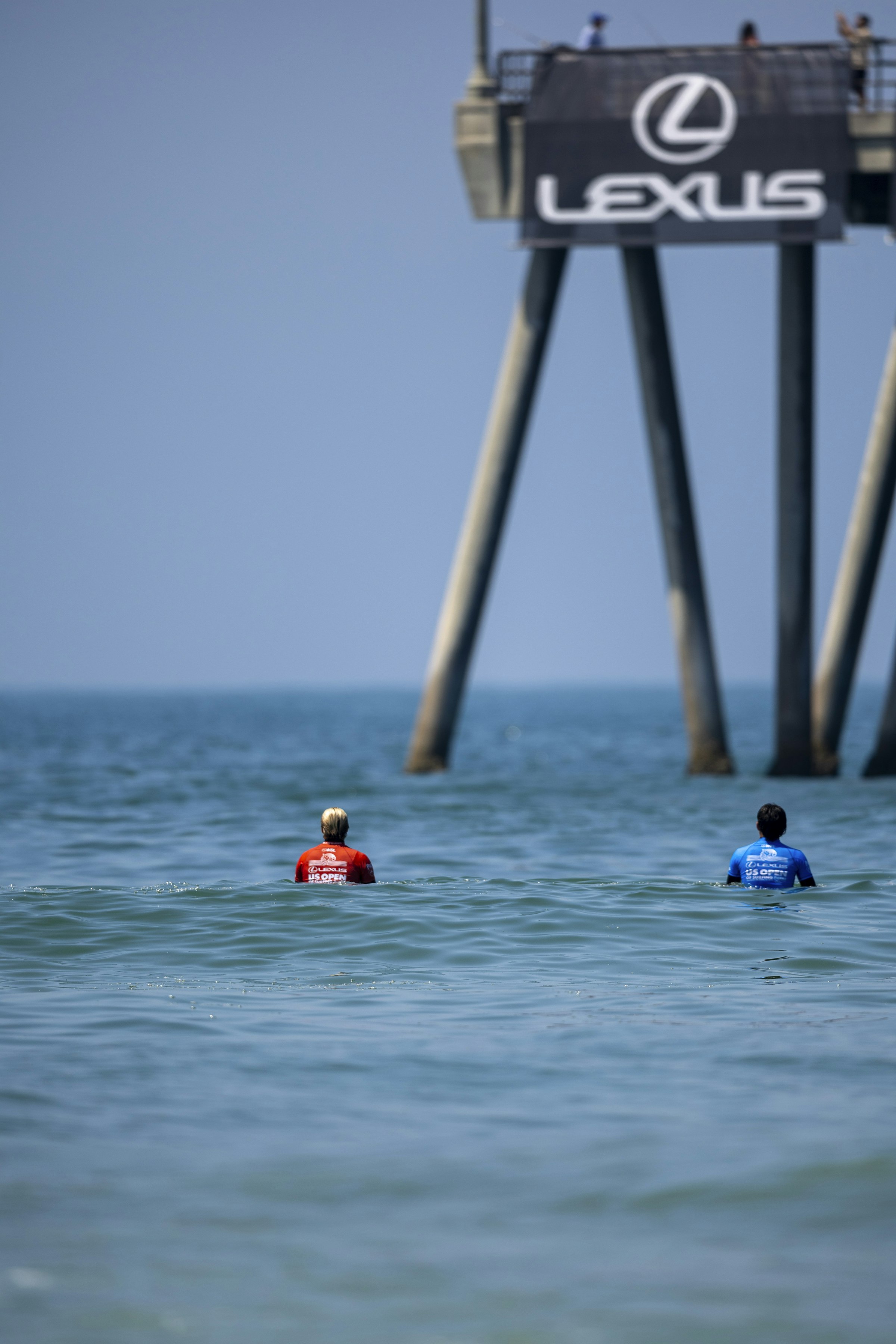 People swimming in the sea beside a pier
