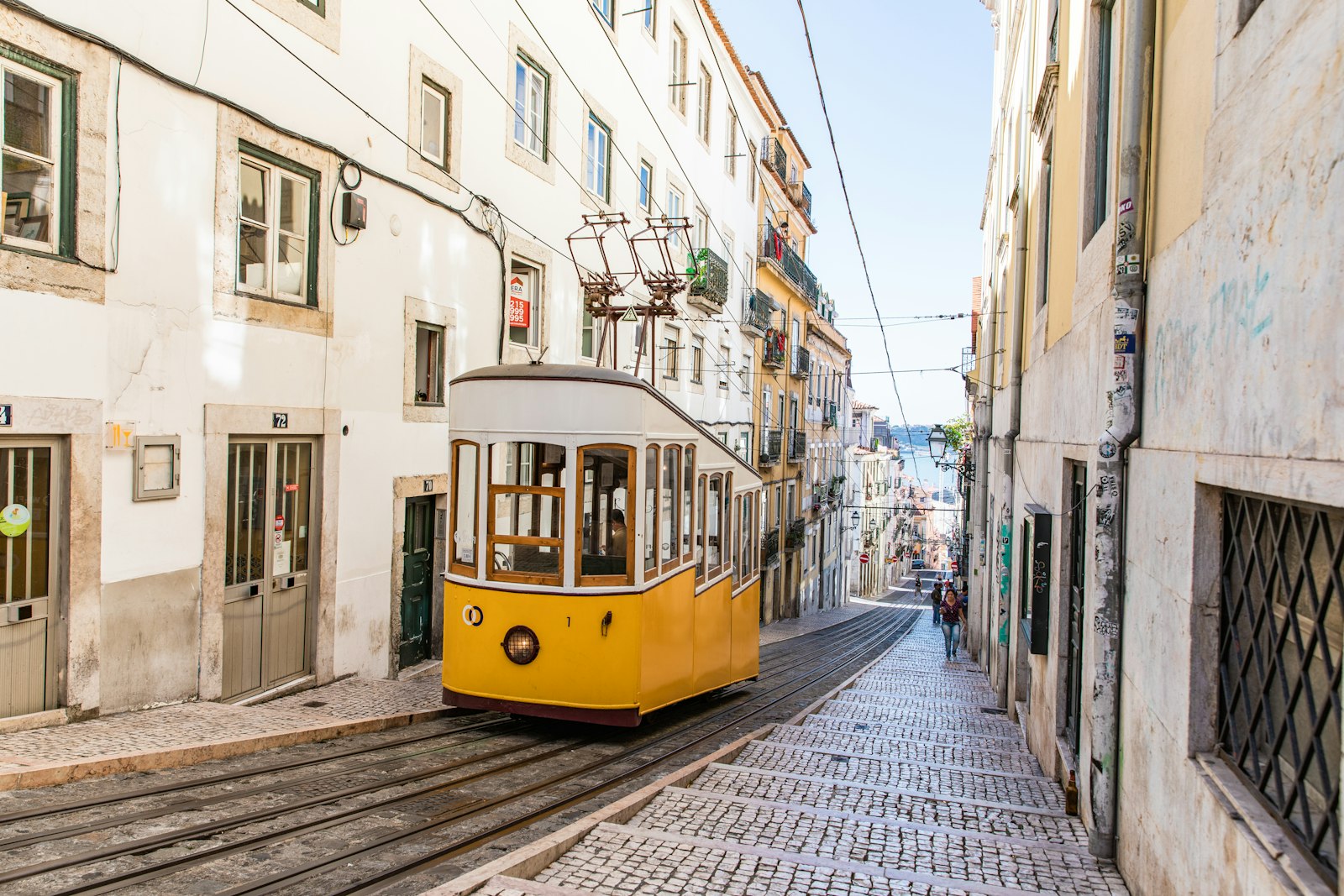 A yellow Lisbon tram climbing a steep street, the Elevador da Bica